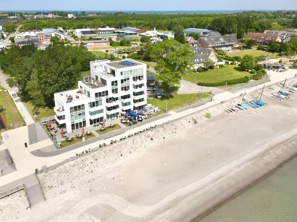 Moderne Villa mit Pool und Strandzugang. Umgeben von Grünflächen und Booten.
