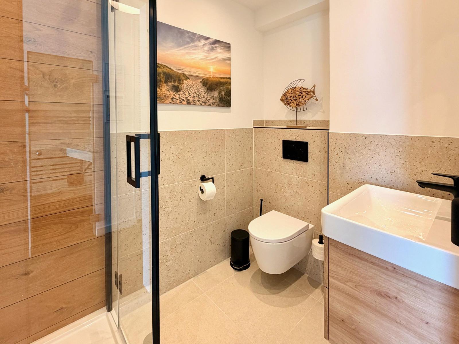 Bad mit Dusche, Toilette und Waschbecken. Wandbild und Fischdekoration.
