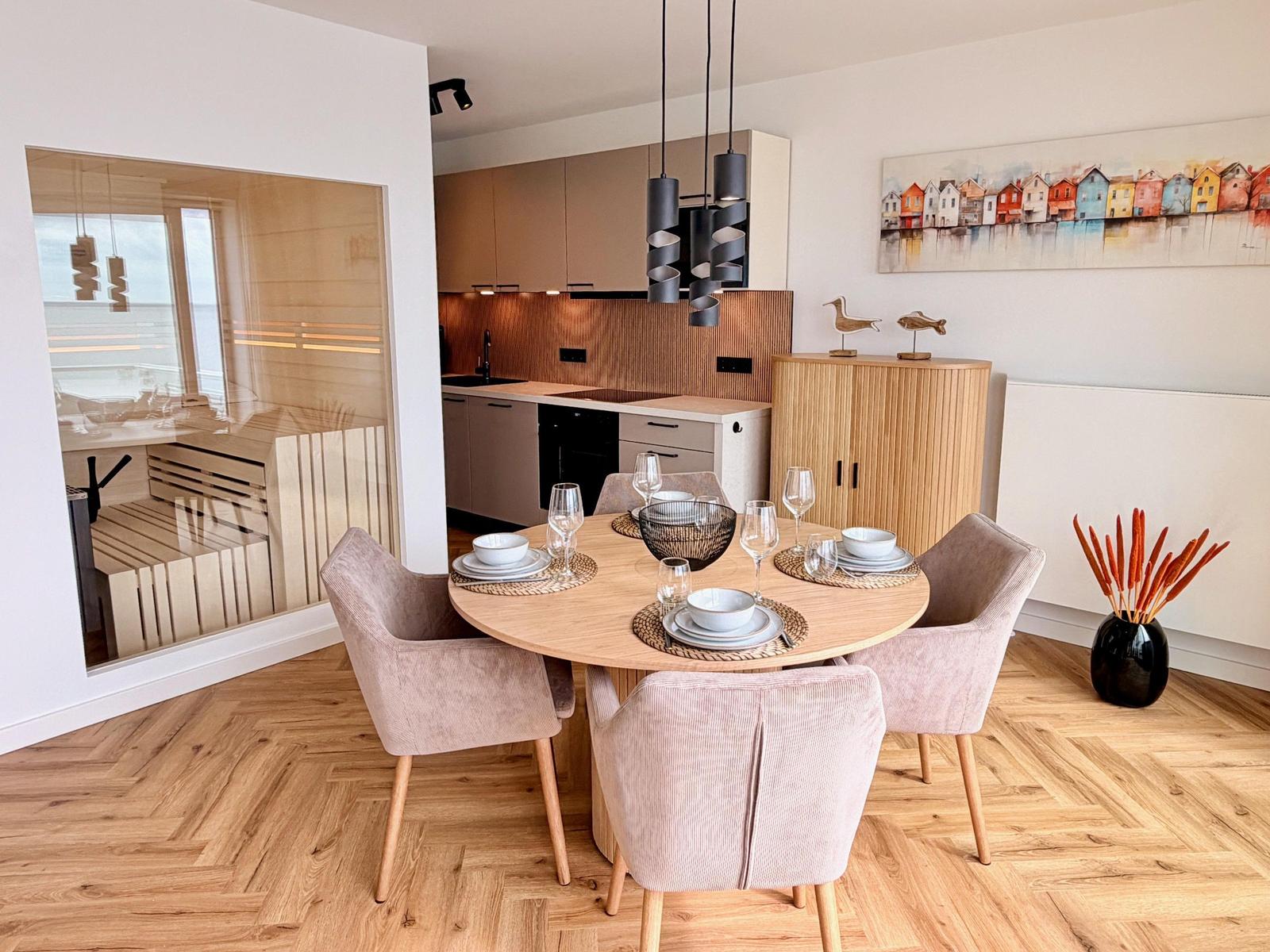 Rundes Esszimmer mit vier Stühlen und Blick in die Küche.