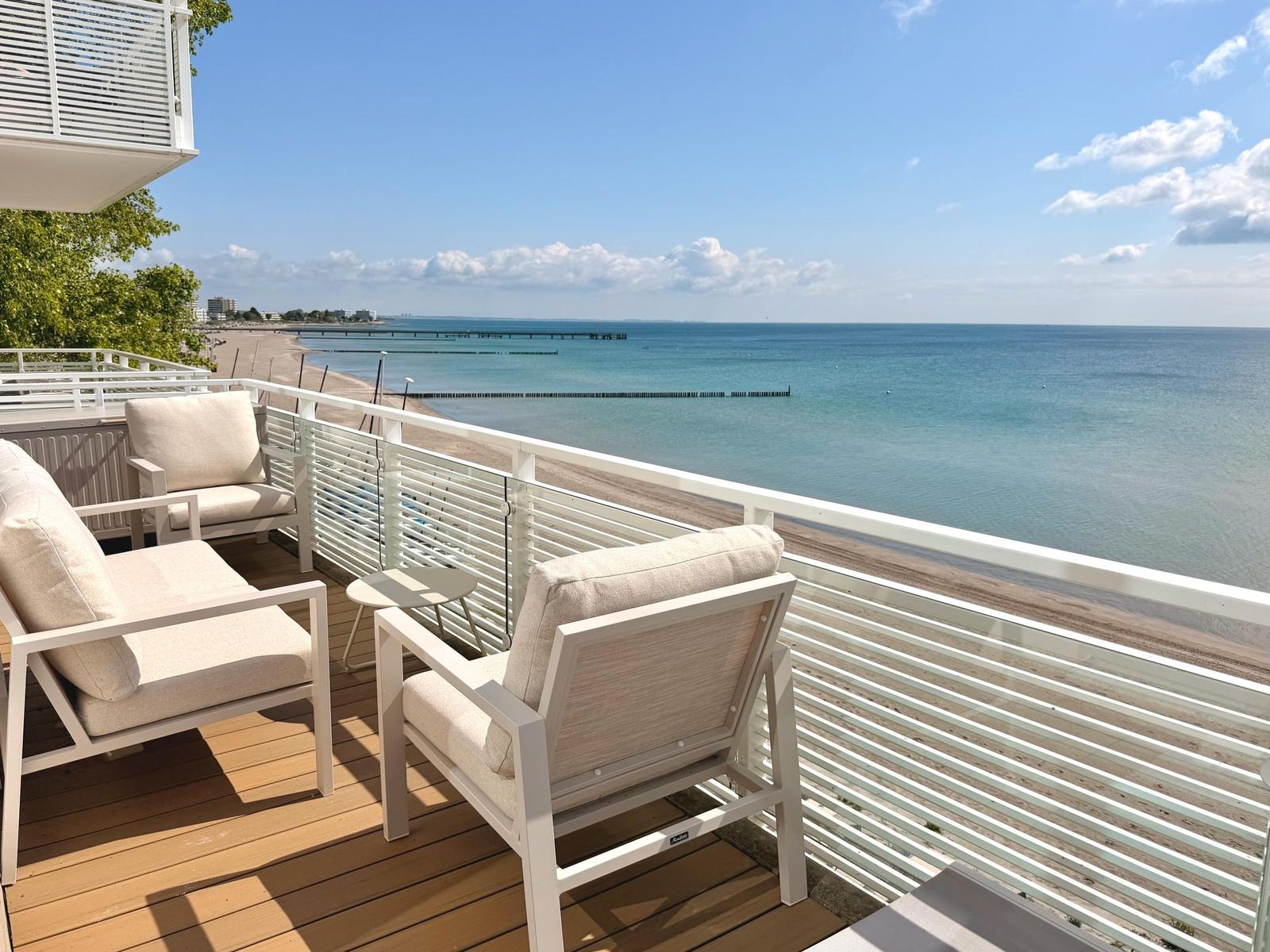 Terrasse mit Sitzgelegenheiten und Blick auf das Meer und Strand.