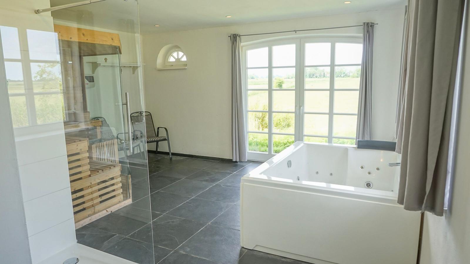 Bad mit Whirlpool, Dusche und Blick auf Felder.