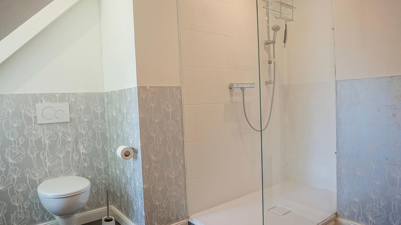Bad mit Dusche und Toilette, Wand mit floraler Tapete