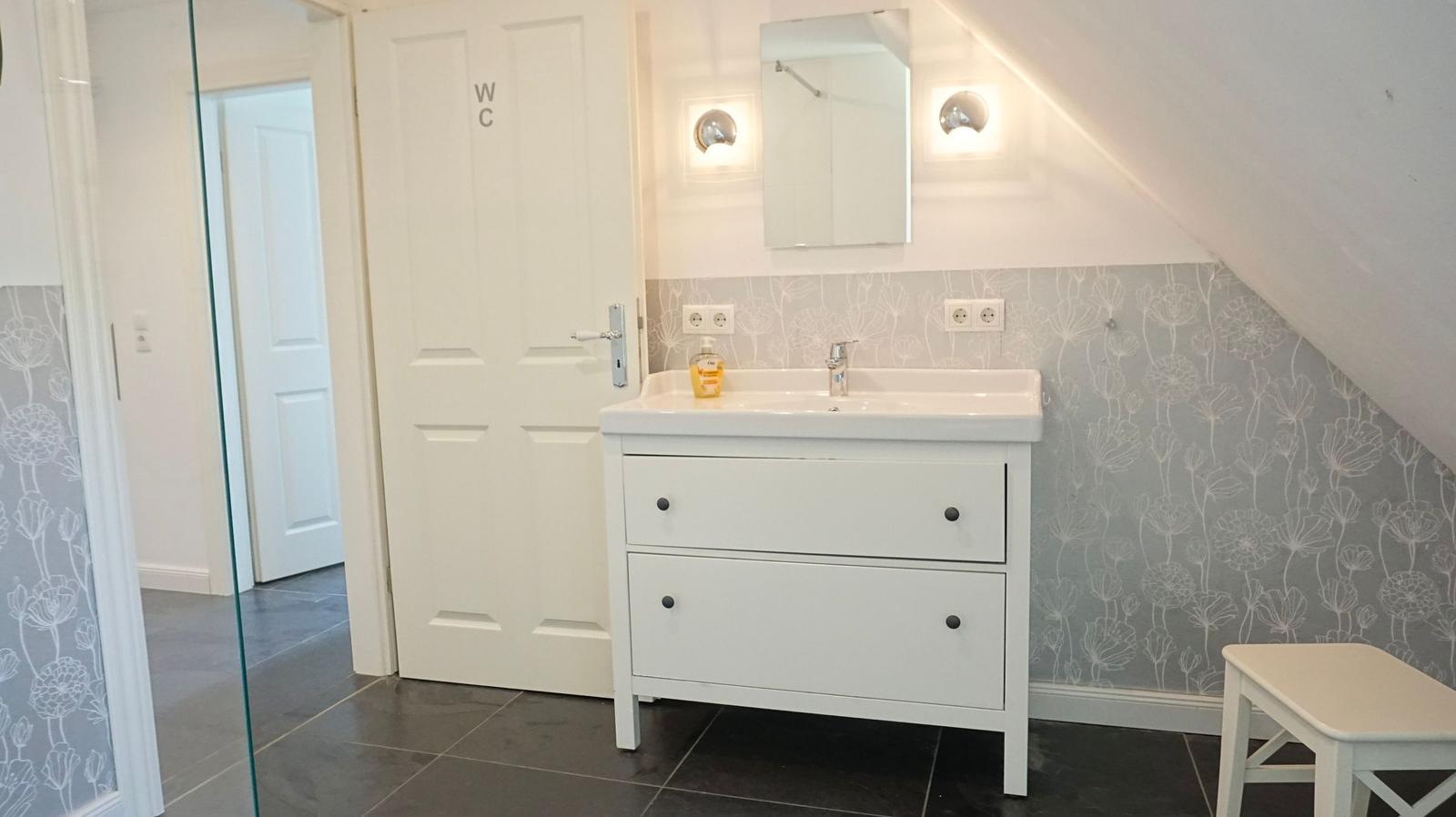 Badezimmer mit Waschtisch, Spiegel und WC-Tür