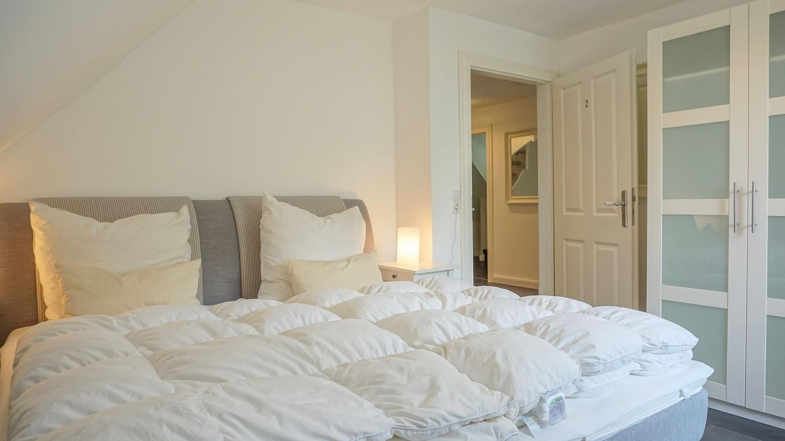 Schlafzimmer mit Doppelbett, Nachttisch und Kleiderschrank.