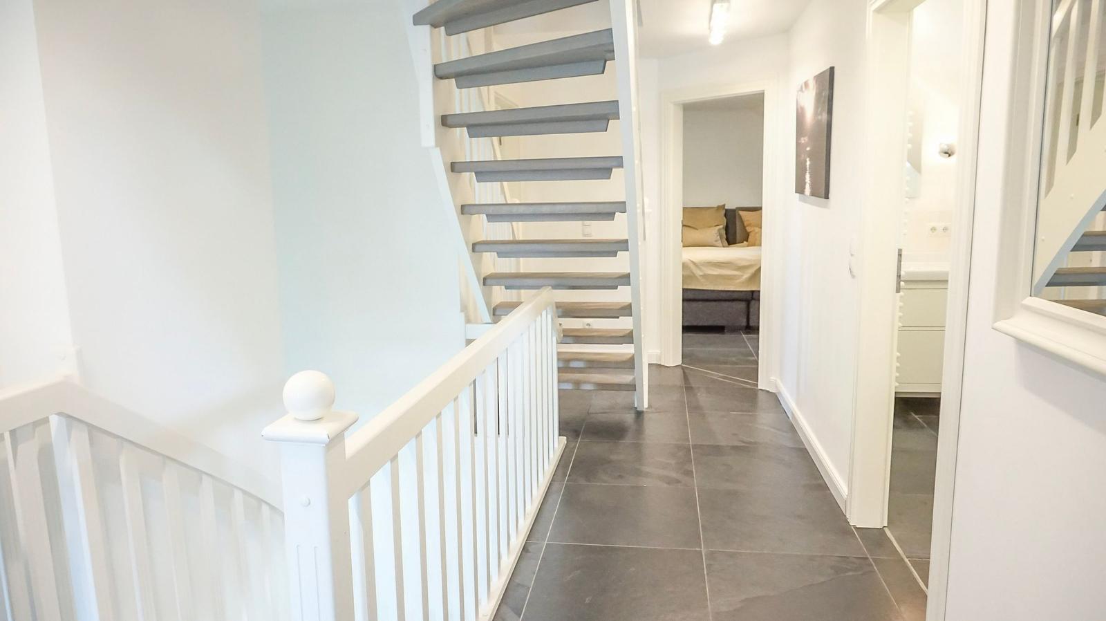 Hausgang mit Treppe und Blick in Schlafzimmer und Bad.