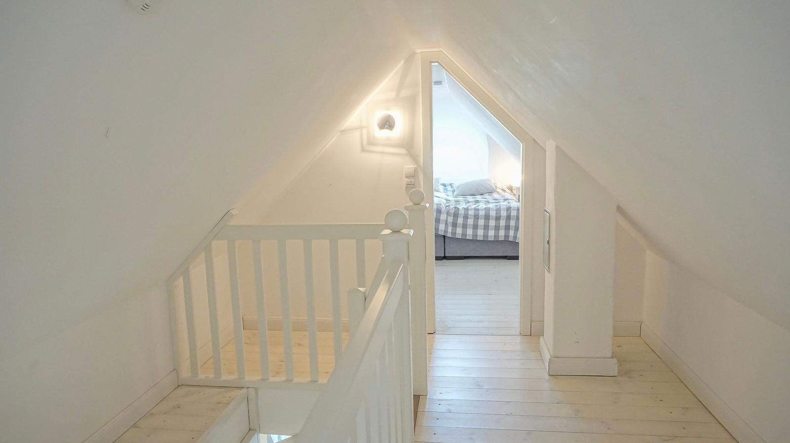 Treppenhaus mit Blick auf Schlafzimmer mit Bett und Holzboden