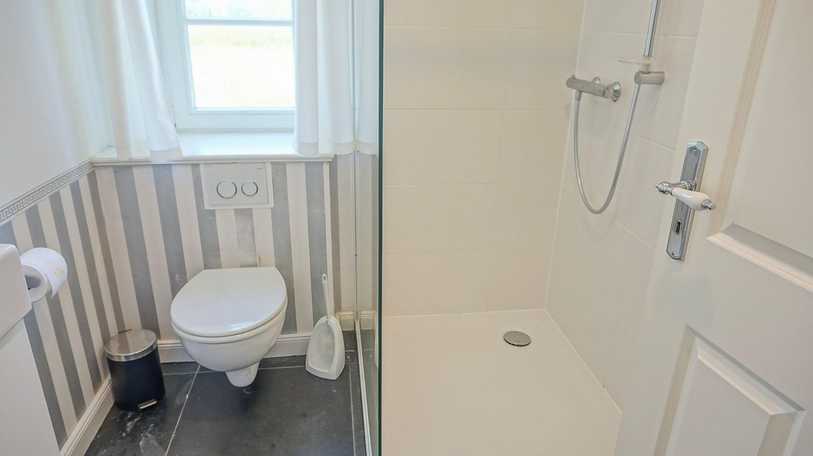 Bad mit Dusche, Toilette und Fenster mit Vorhang