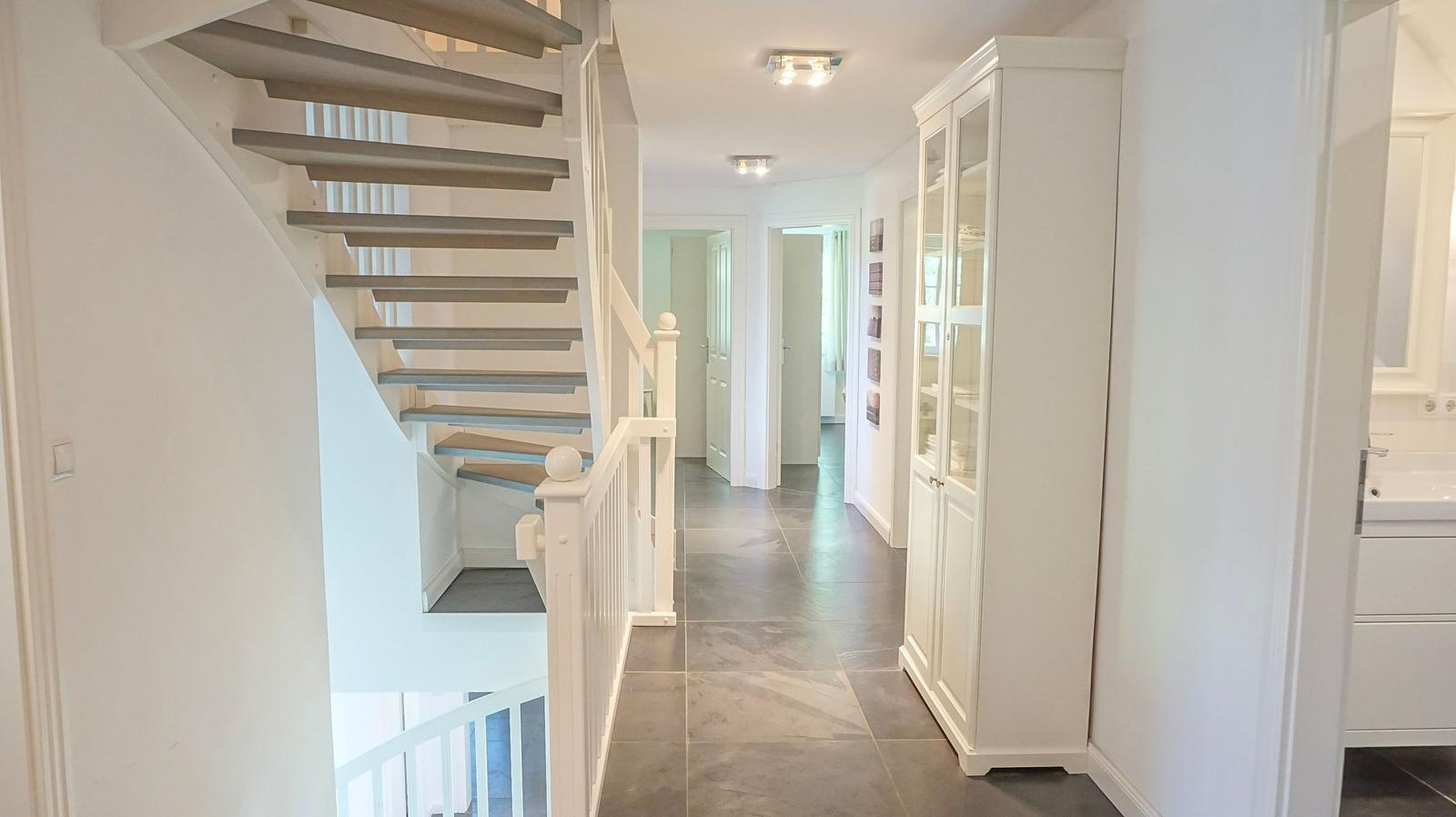 Hausflur mit Treppe, Schrank und Blick in angrenzende Räume.