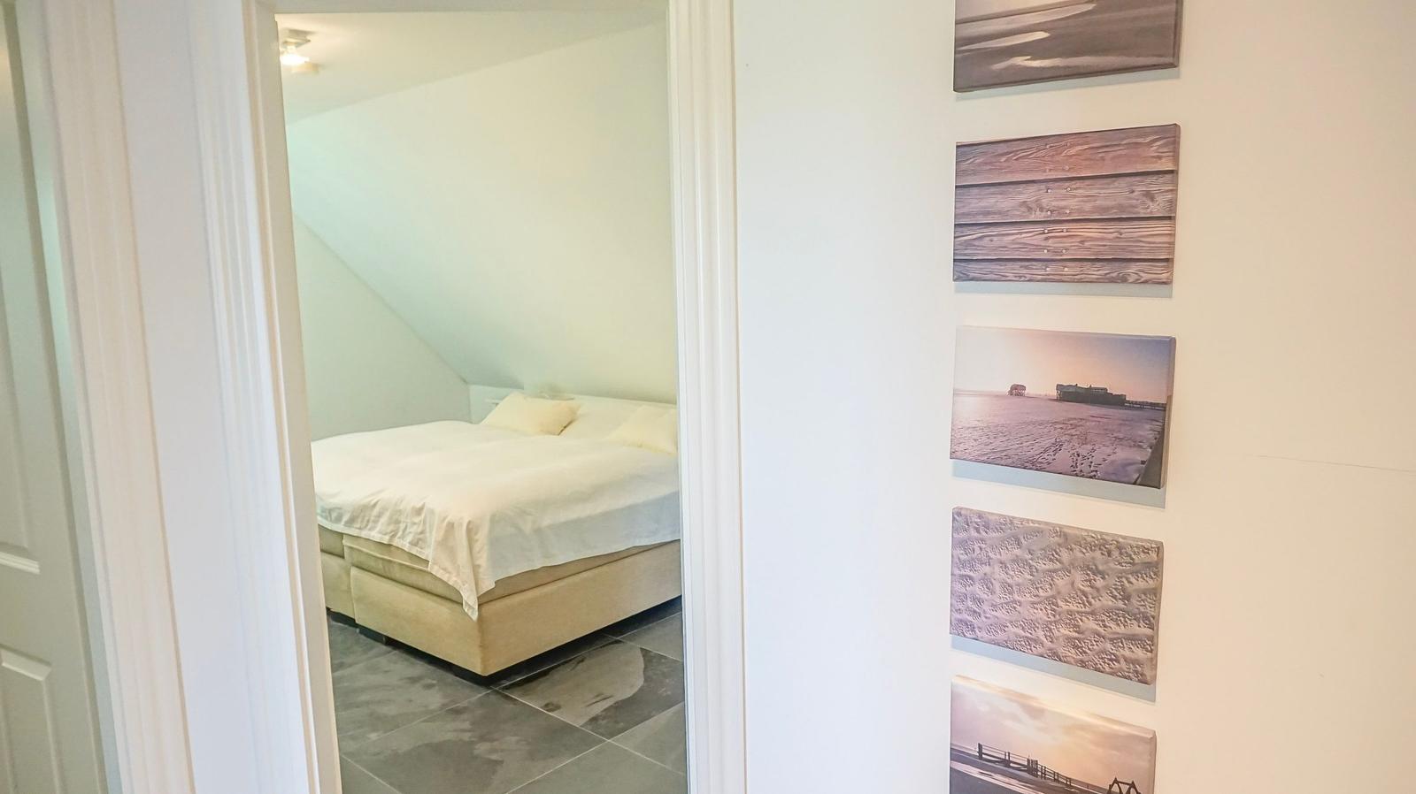 Schlafzimmer mit Dachschrägen und Bett. Wanddekoration mit Bildern.