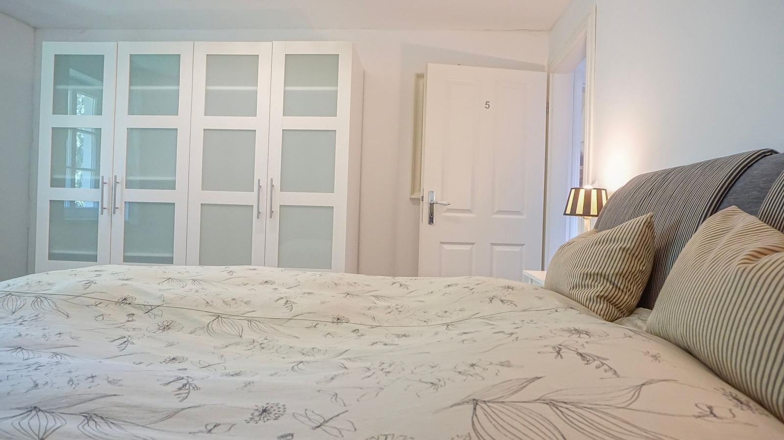 Schlafzimmer mit Bett, Kleiderschrank und Tür mit Nummer 5