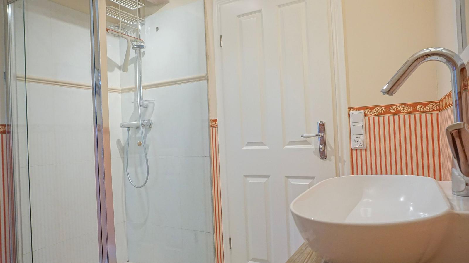 Badezimmer mit Dusche, Waschbecken und Tür
