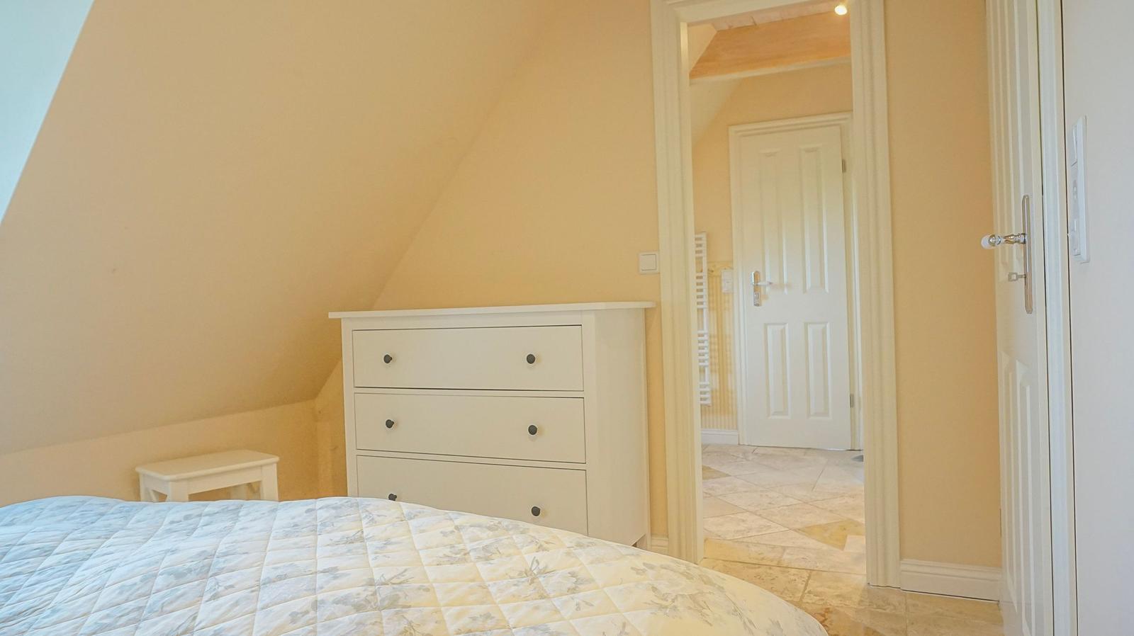 Schlafzimmer mit Bett, Schrank und Tür zum Flur.
