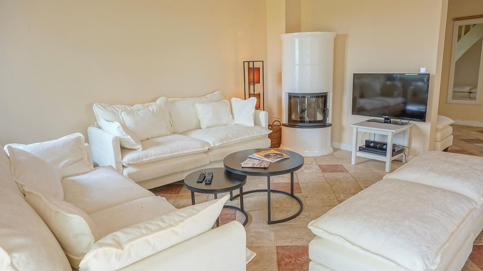 Wohnzimmer mit weißem Sofa, Kamin und Fernseher auf Tisch.