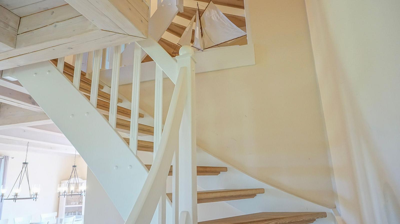 Treppenhaus mit weißer Balustrade und Holzstufen, Schiffmodell an der Decke.