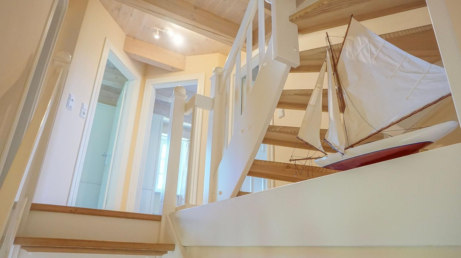 Treppenhaus mit hölzernen Balken und Segelschiffmodell an der Wand