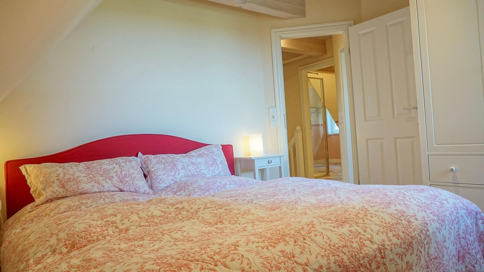 Schlafzimmer mit Bett, Nachttisch und Tür zum Bad