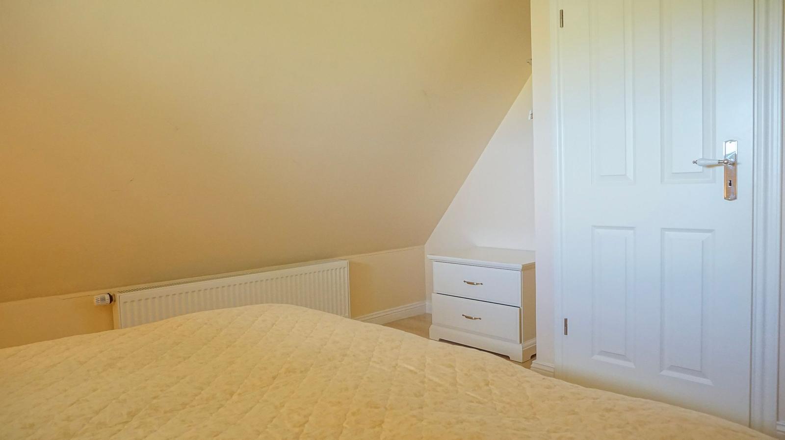 Schlafzimmer mit Bett, Nachttisch und Tür