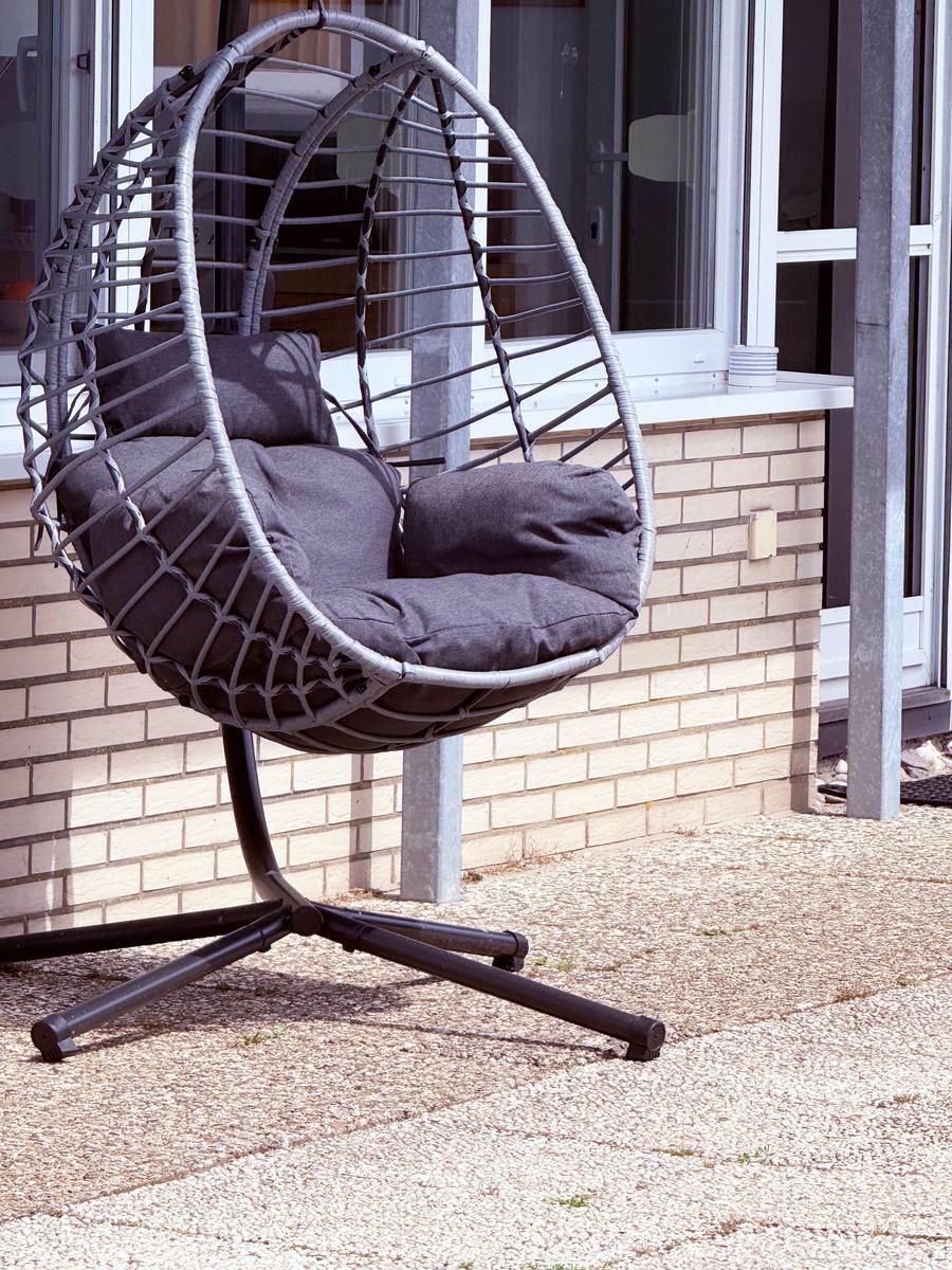 Eierschalen-Schaukelstuhl mit Kissen auf Terrasse vor Hauswand