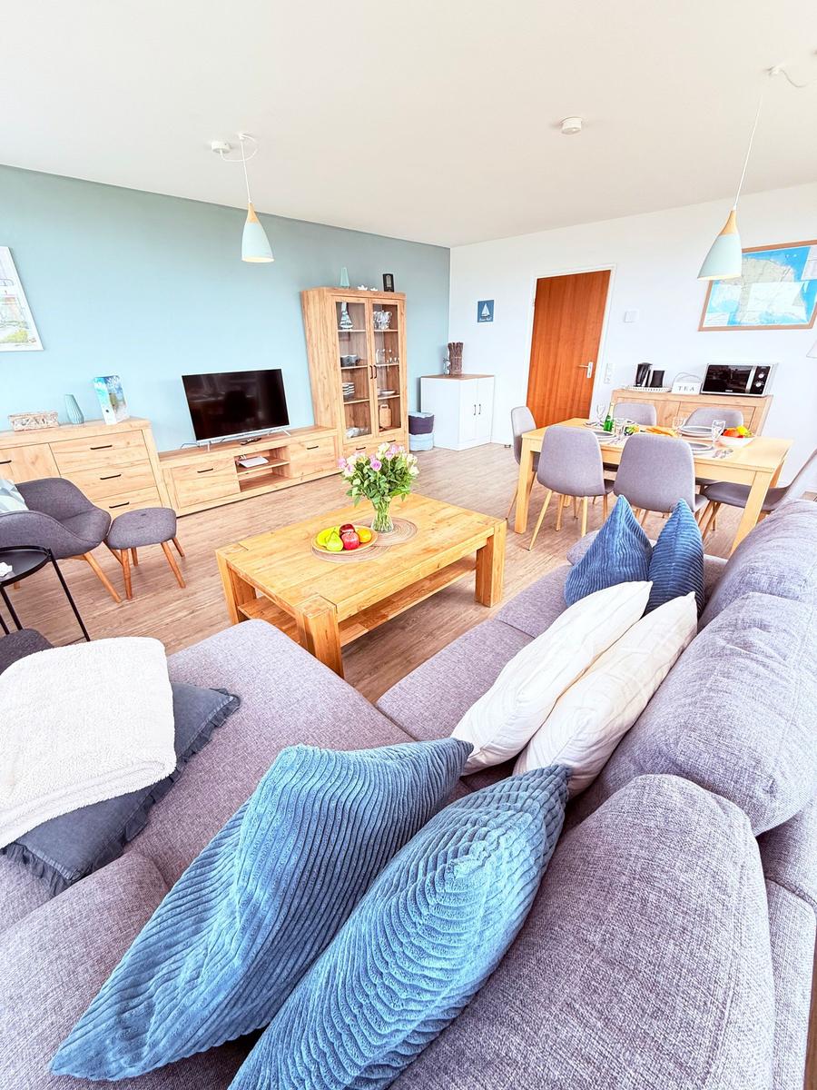 Wohn- und Essbereich mit Sofa, Esstisch und Fernseher.