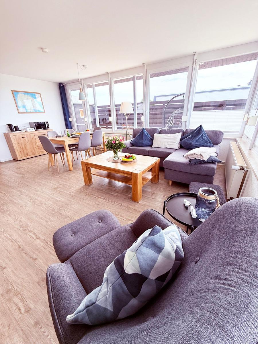 Wohn- und Essbereich mit Sofa, Tisch und Fenster zur Terrasse.