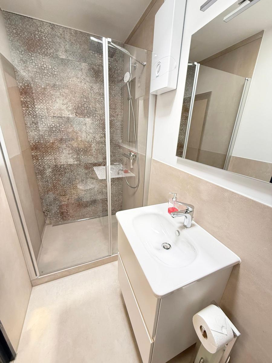 Badezimmer mit Dusche, Waschbecken und Spiegel