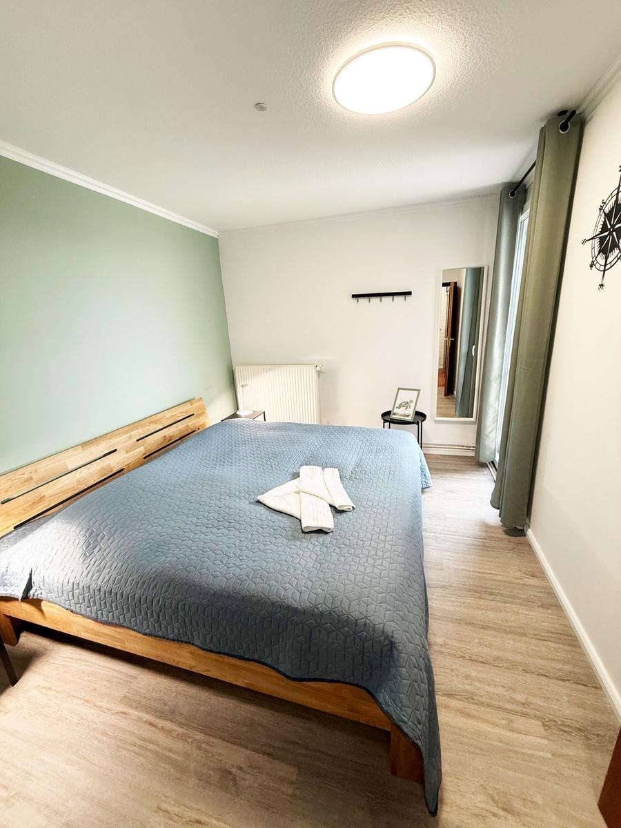 Schlafzimmer mit Holzbett, blauer Bettwäsche und Holzboden.