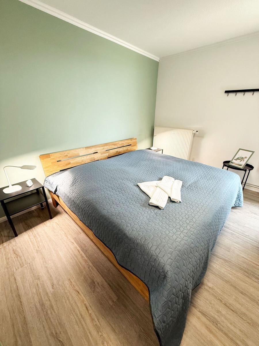 Schlafzimmer mit Bett, Nachttisch und Holzboden.