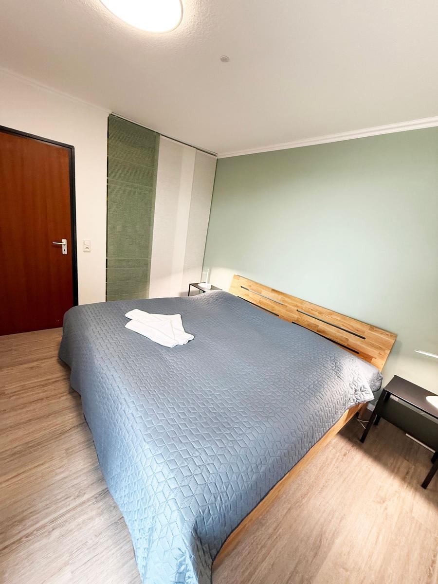 Schlafzimmer mit Bett, Holzfußboden und grüner Wand