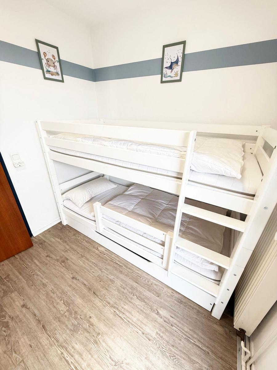 Zimmer mit weißem Doppelstockbett und Holzboden