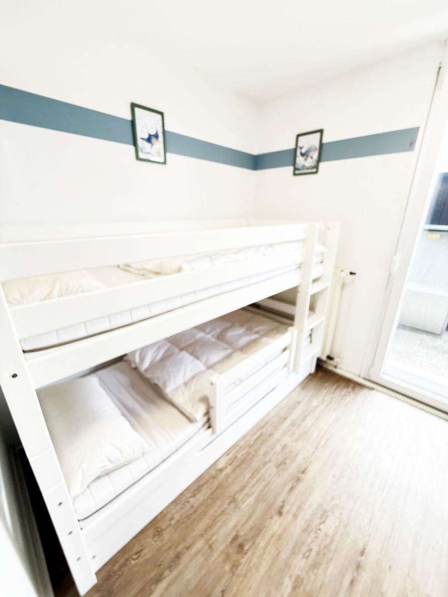 Zimmer mit Doppelstockbett, Holzboden und Fenster zur Terrasse.