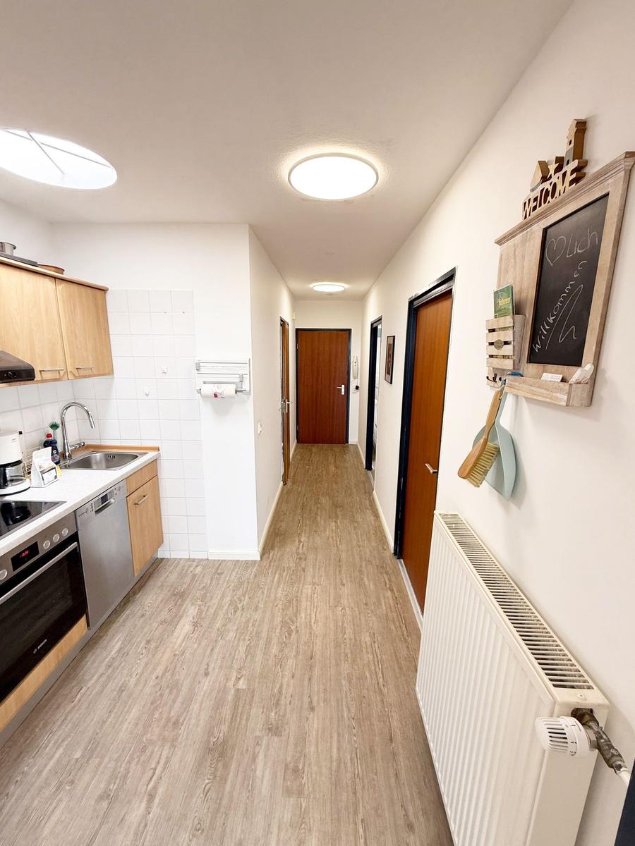 Küche mit Holzwerkstoffe und Fliesen. Flur mit Türen und Wandschrank.