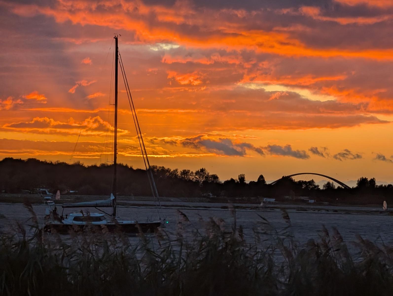 Segelboot vor Sonnenuntergang mit Brücke im Hintergrund