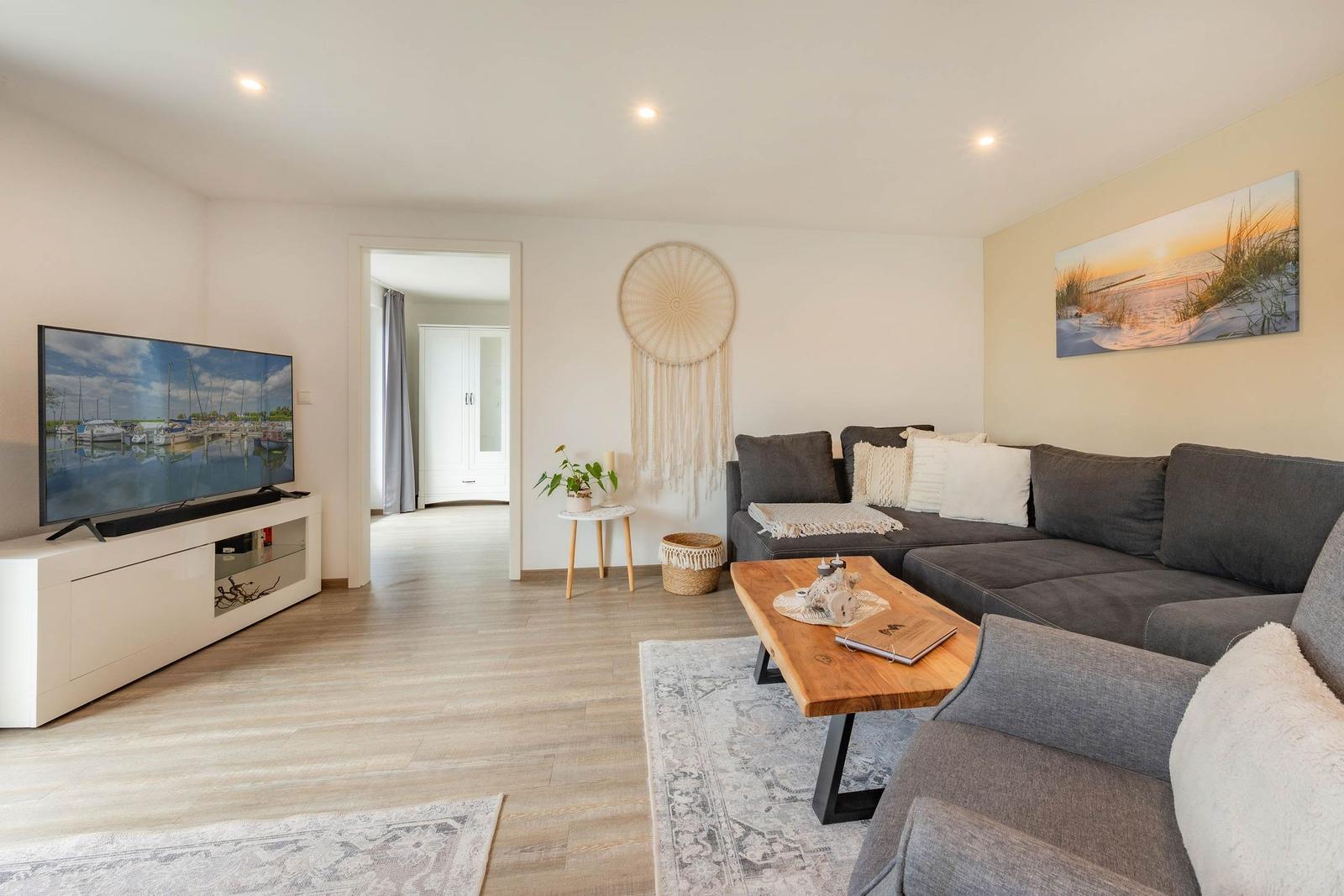 Wohnzimmer mit Sofa, Fernseher und Holztisch