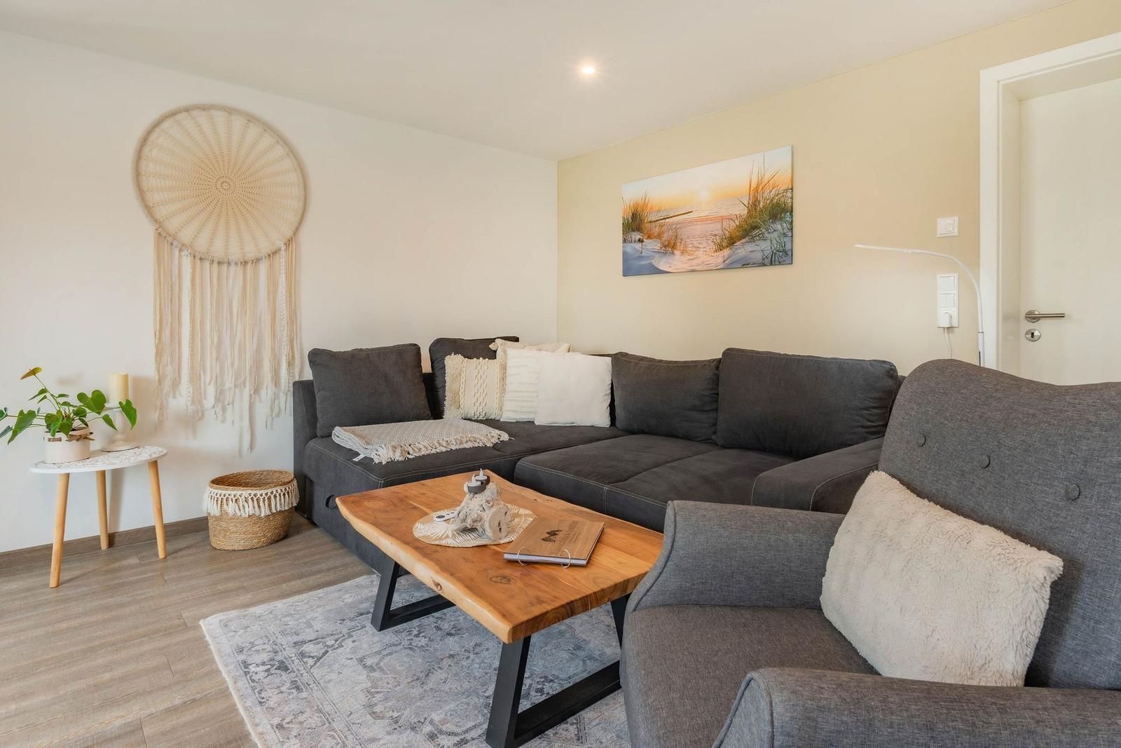 Wohnzimmer mit grauem Sofa, Holztisch und Wandbild