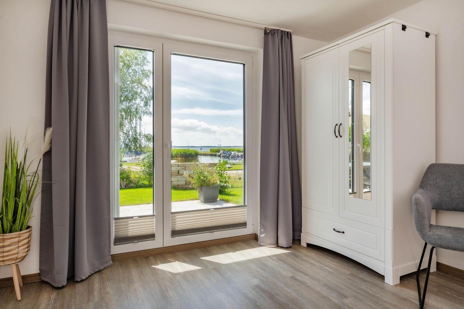 Zimmer mit Blick auf Hafen, weißer Schrank und graue Vorhänge.
