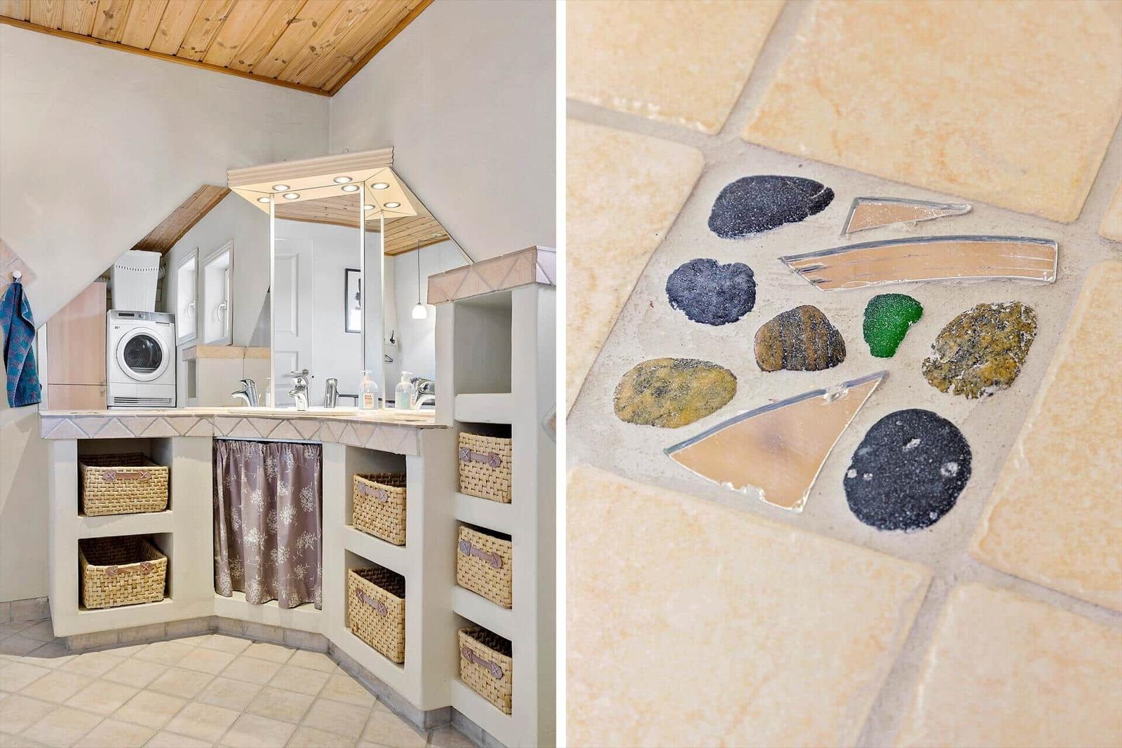 Badezimmer mit Waschmaschine und Mosaikboden aus Steinen und Glas.