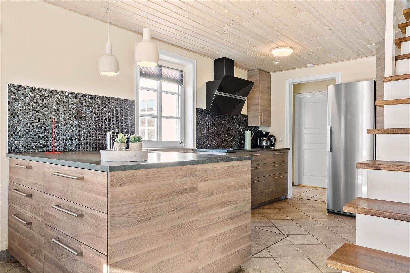 Moderne Küche mit Holzoberflächen, Edelstahlkühlschrank und Mosaikrückwand.