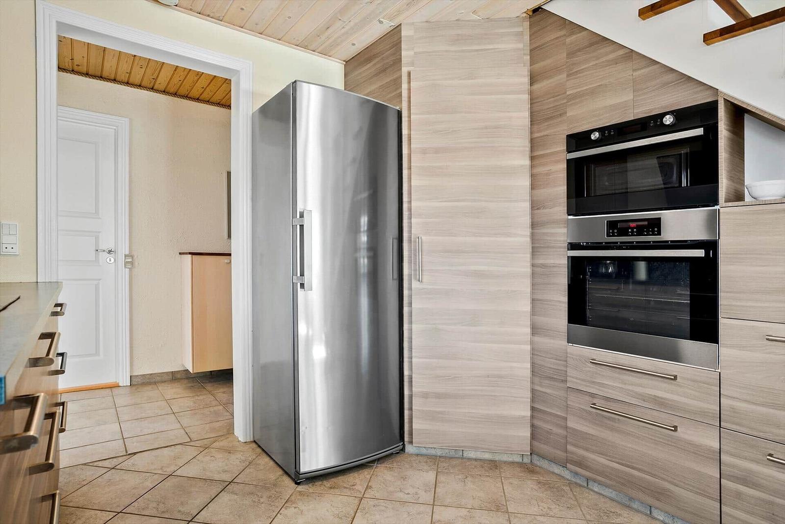 Küche mit Edelstahl-Kühlschrank und eingebauten Backofen und Mikrowelle.