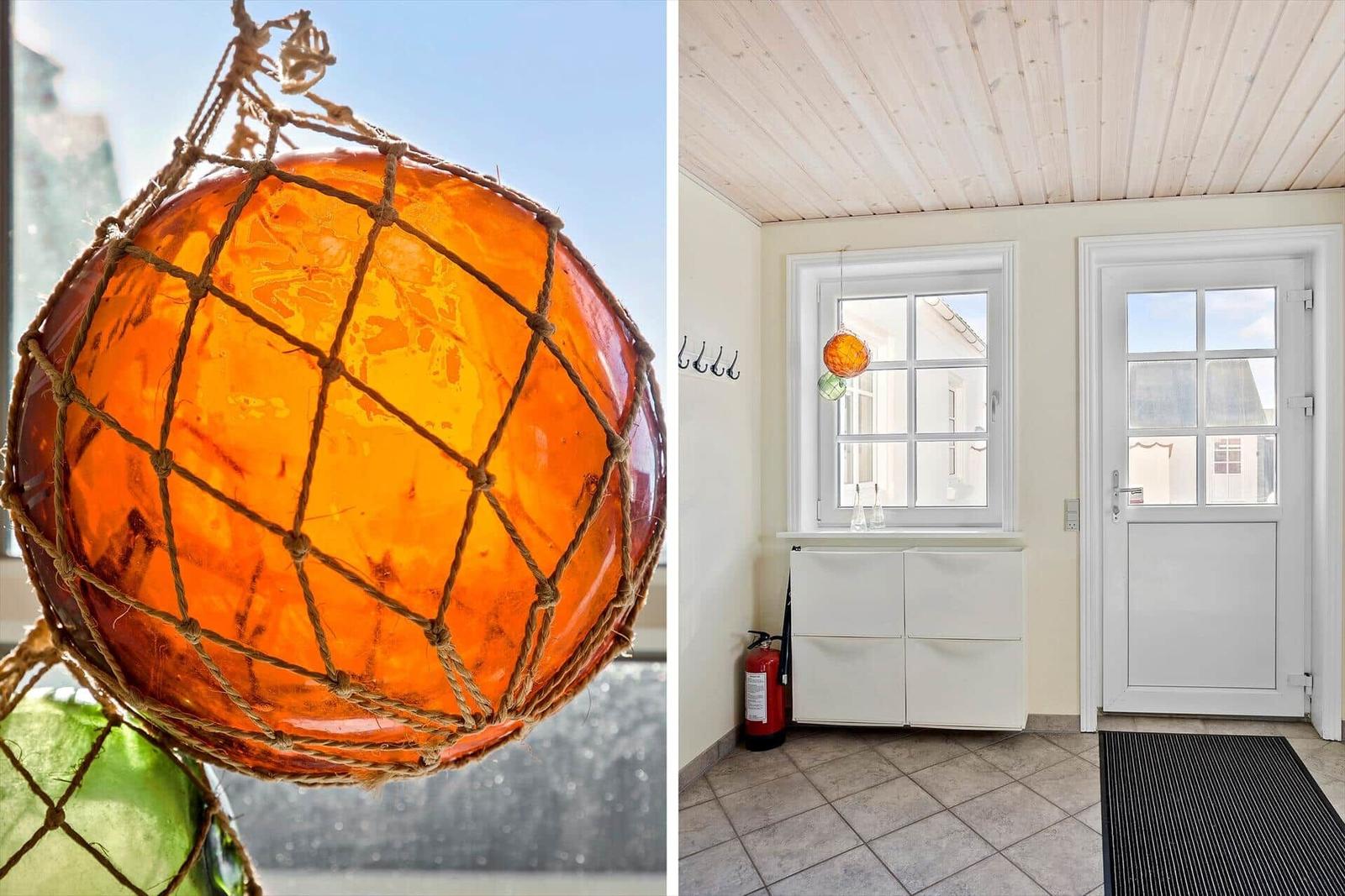 Ein orange-gelber Buoyschmuck hängt im Fenster. Ein Eingangsbereich mit weißer Tür und Schrank.
