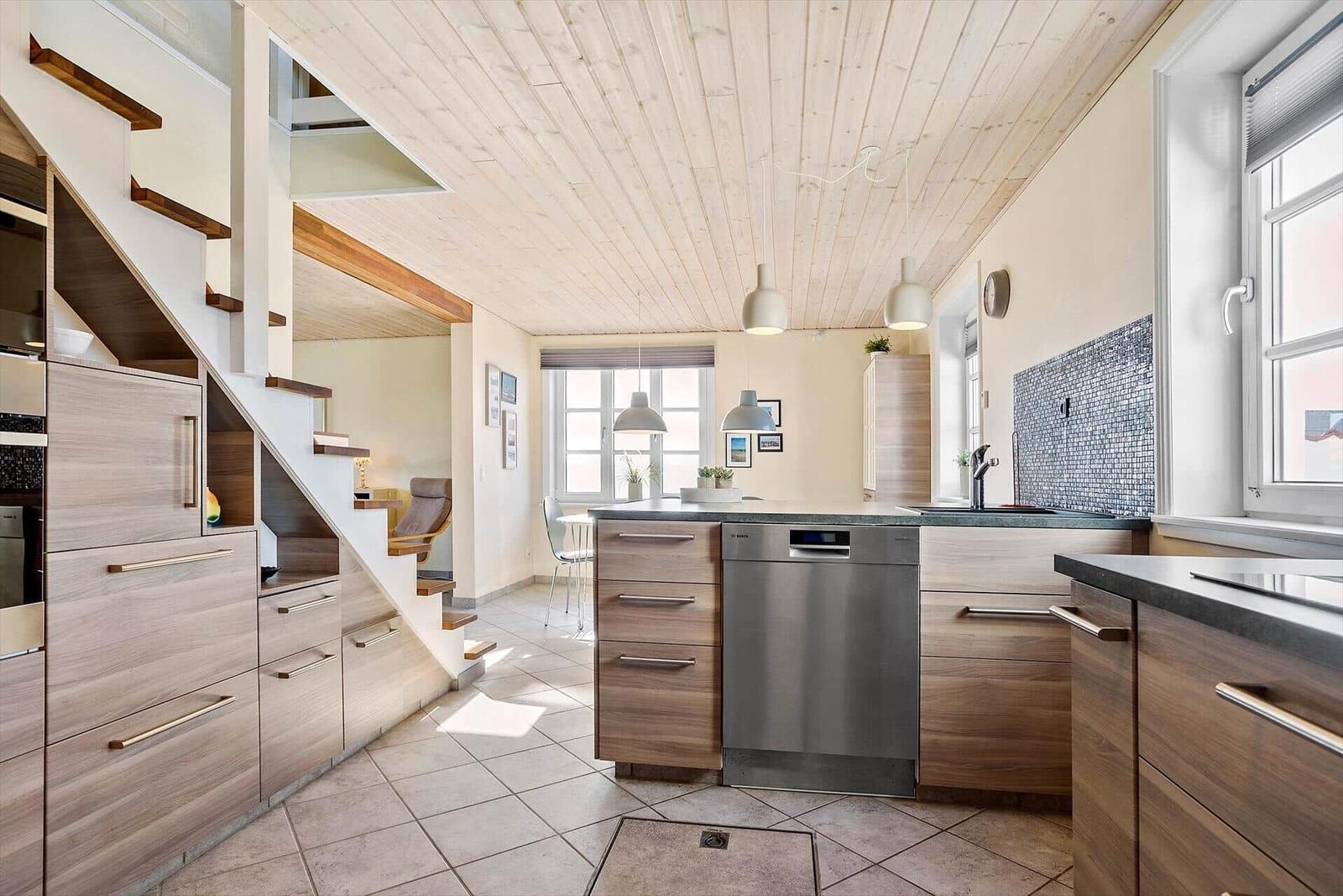 Küche mit Holzdecke, Edelstahlspüle und Treppenaufgang