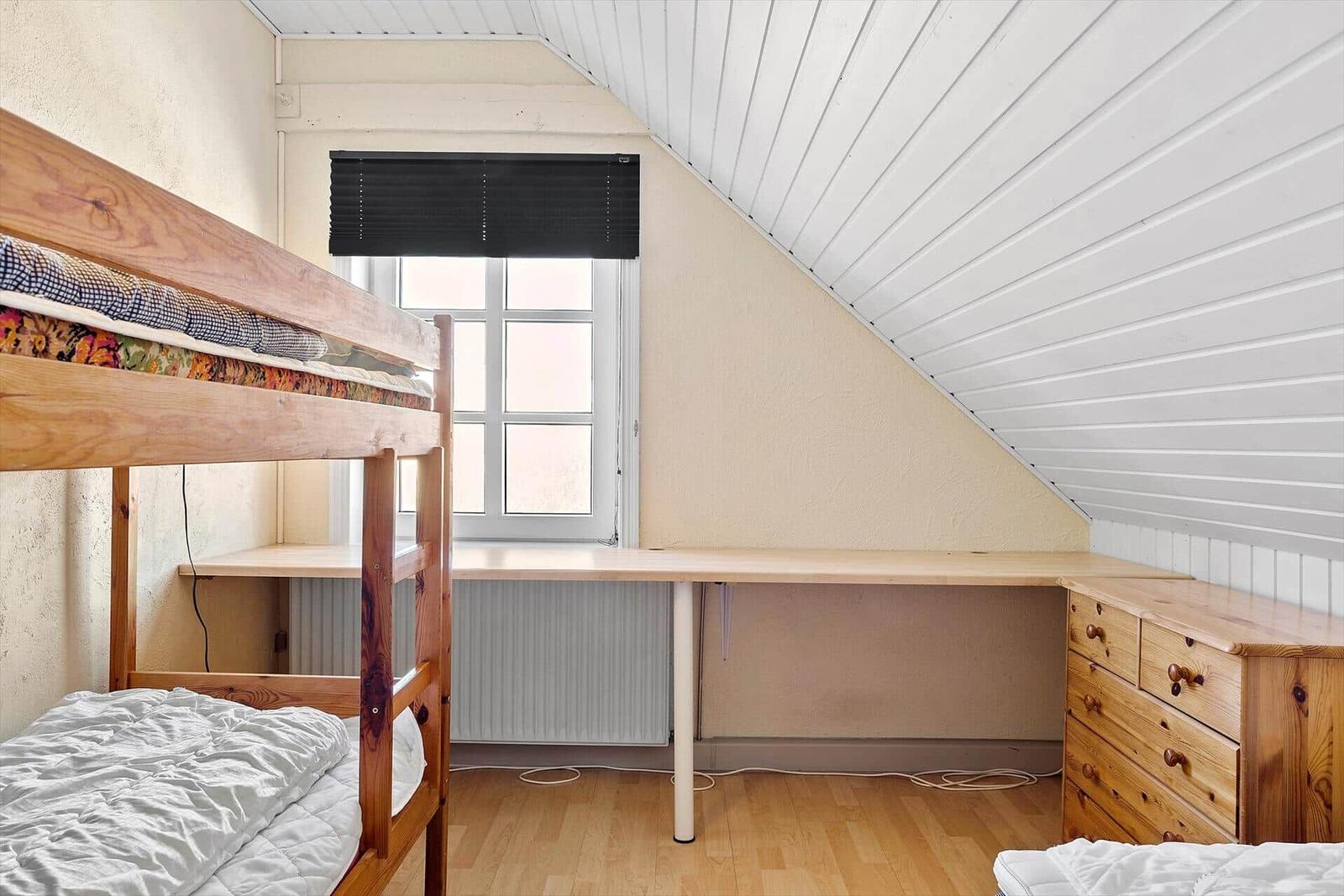 Zimmer mit Doppelstockbett, Schreibtisch und Schrank unter schrägem Dach