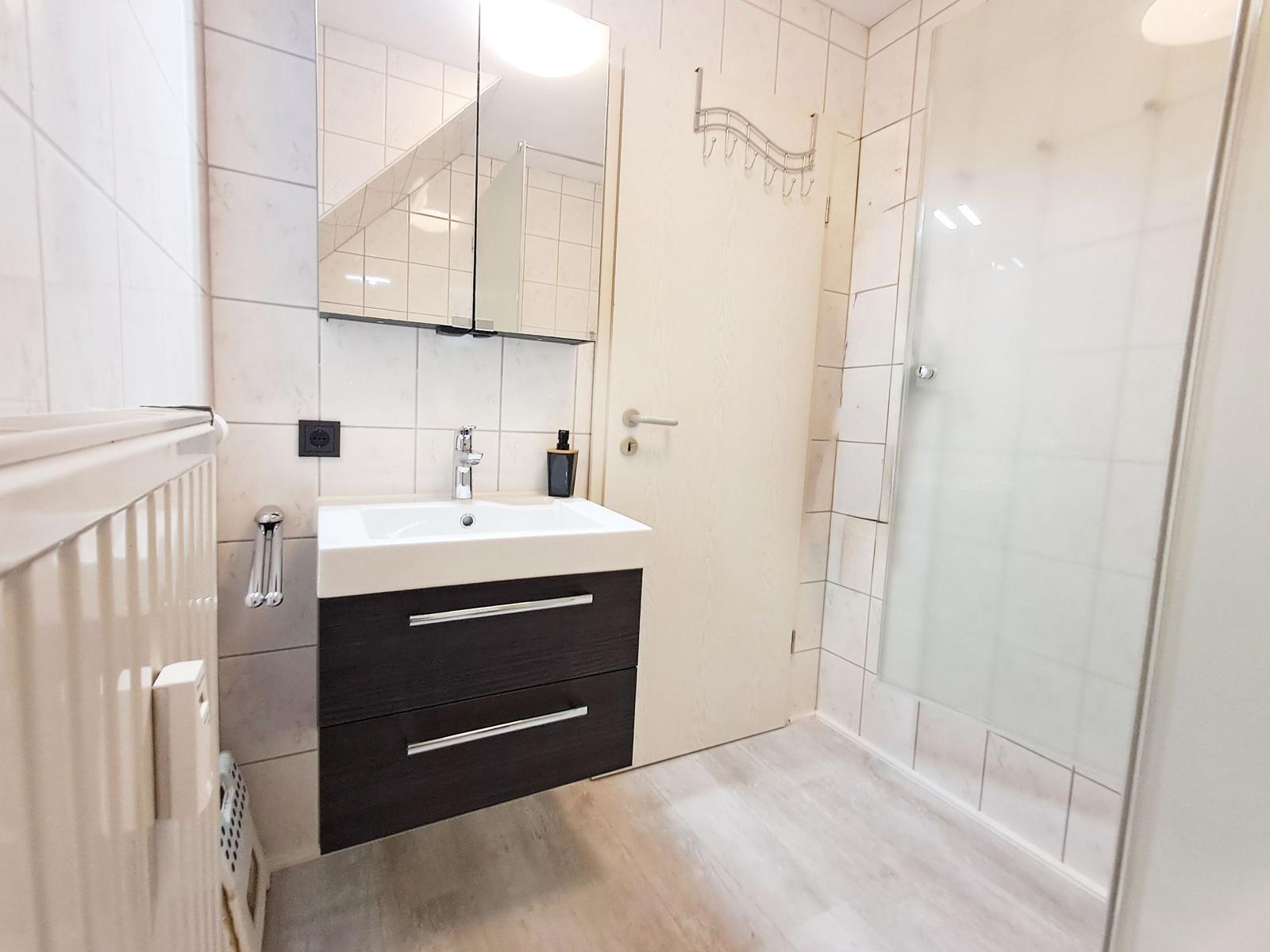 Badezimmer mit Waschbecken, Spiegel und Dusche.