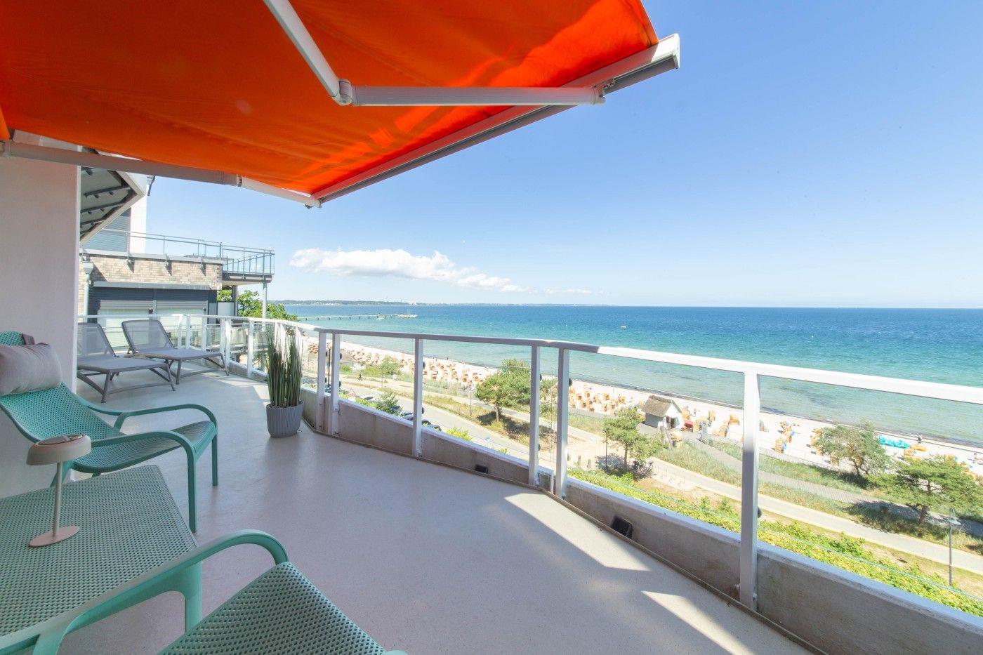 Terrasse mit orangefarbenem Markisenüberdachung und Meerblick.