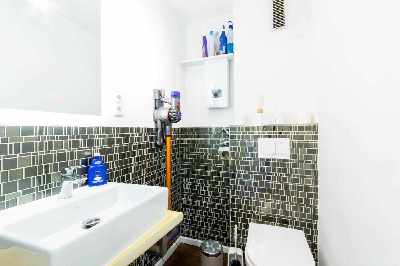 Badezimmer mit Waschbecken, Toilette und Mosaikwand