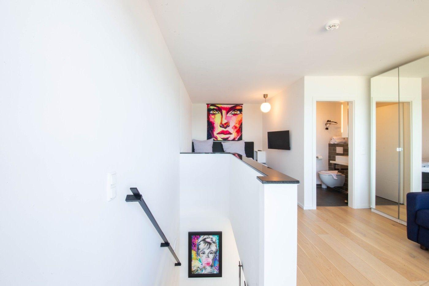 Haus mit Treppenhaus, Wandbildern und Blick in Bad und Schlafzimmer