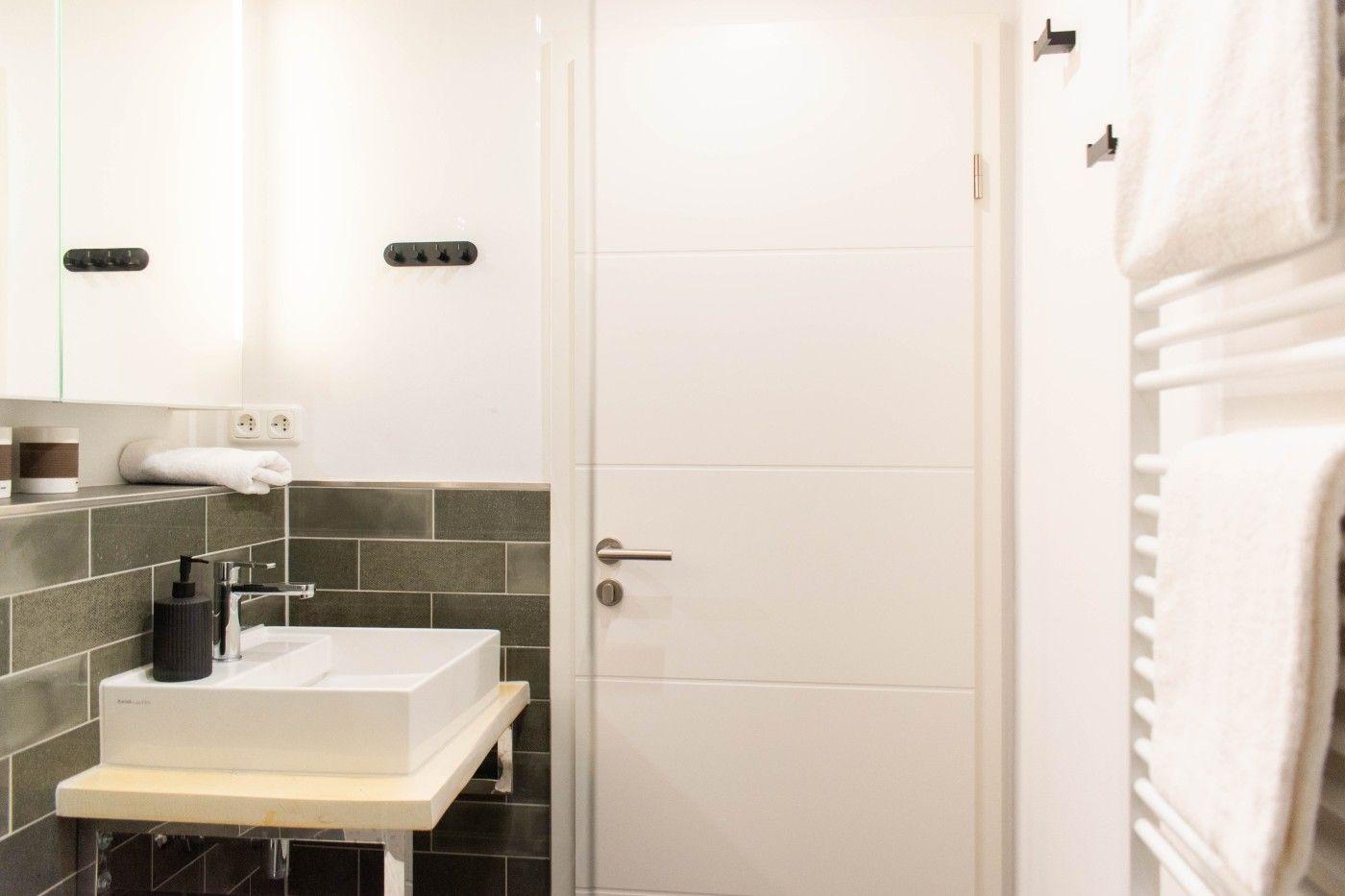 Badezimmer mit Waschbecken, Spiegel und Handtuchhalter.