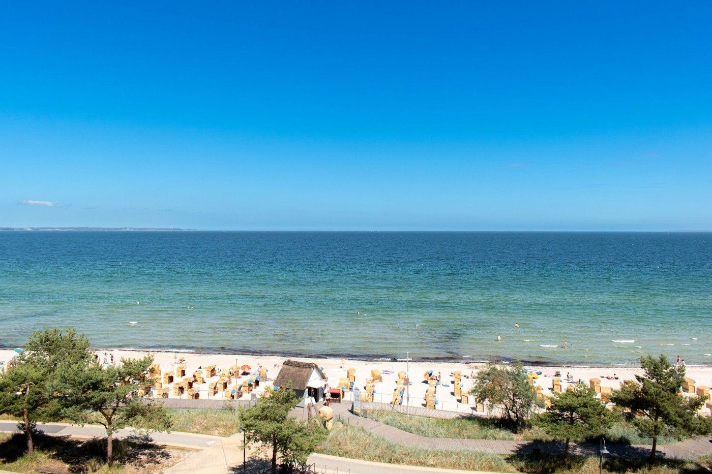 Strand mit Sandkästen und blauem Meer unter klarem Himmel.