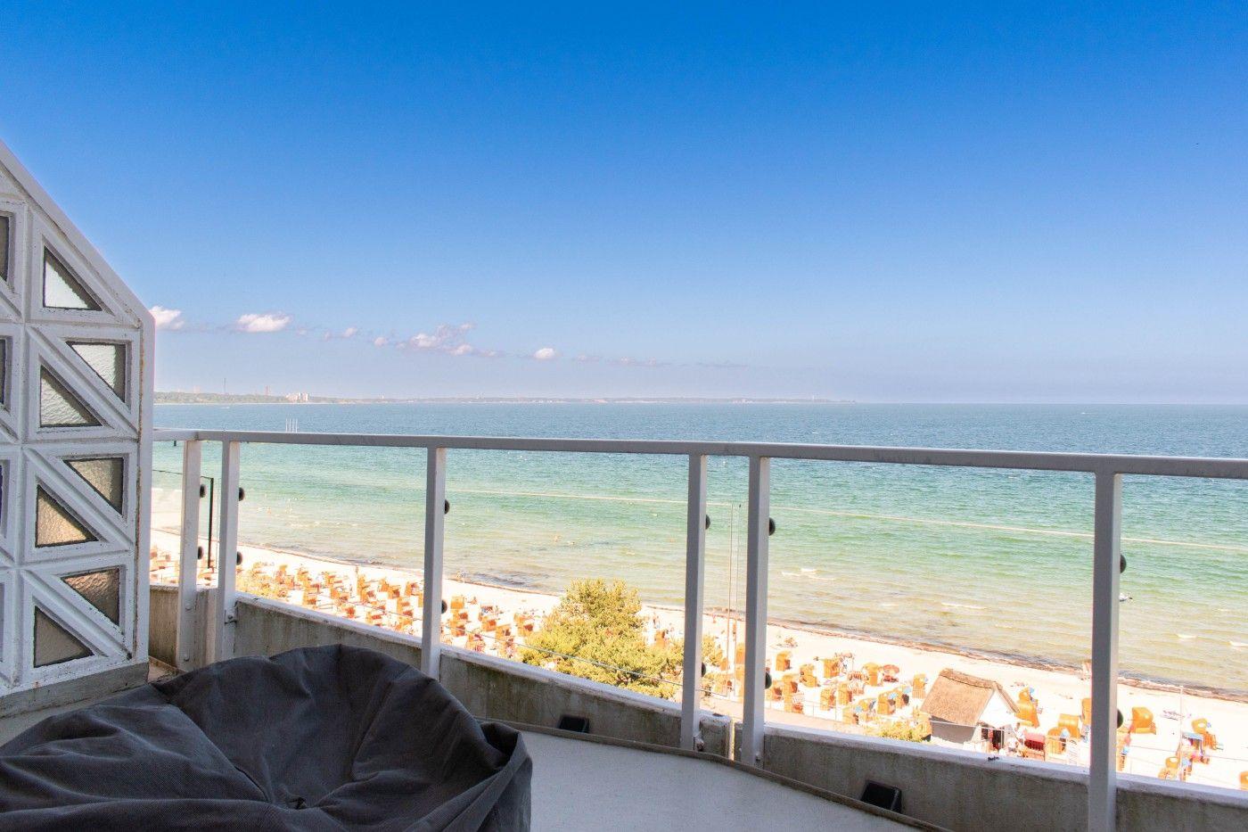Terrasse mit Meerblick, Sonnenliegen und Strand im Hintergrund.