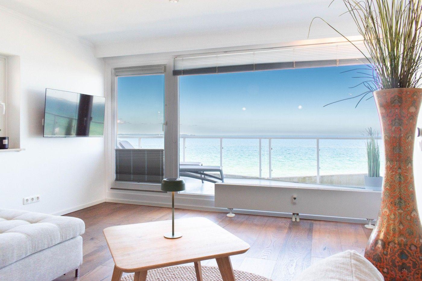 Wohnzimmer mit Meerblick, Holzboden, Sofa und TV an der Wand.