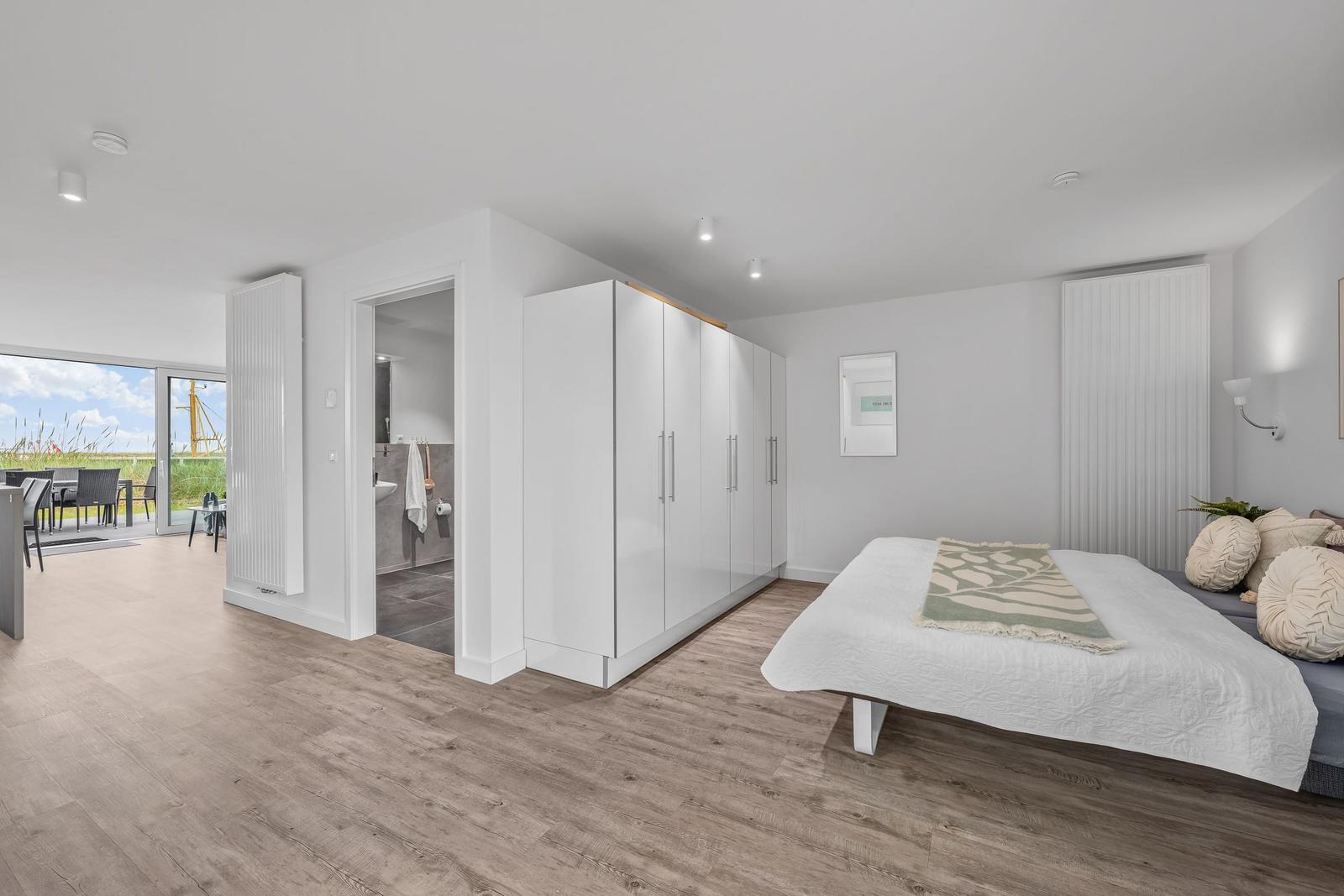 Schlafzimmer mit Bett, Kleiderschrank und Blick auf Terrasse